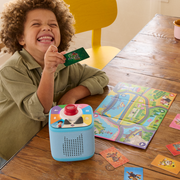 Child playing with a toy and cards on a wooden table
