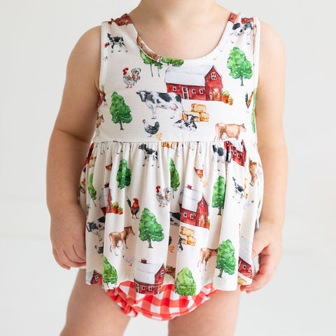 Toddler in bloomer set. Top is a Country farm print on a cream background.  Bloomers are red and white country checkered.