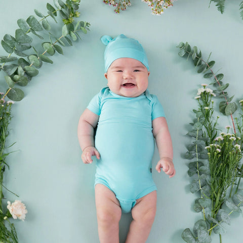 Baby wearing This short sleeve bodysuit is a solid robin's egg blue with a blue knotted hat. Hat is not included