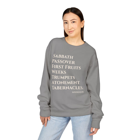 Person wearing a gray sweatshirt with religious text on a white background