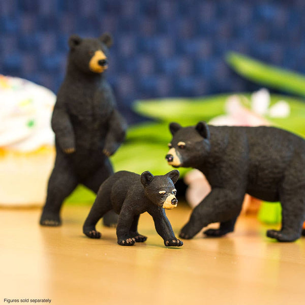 Family of black bears with one bear standing up on his hind legs, one bear on all fours, and a baby cub out frnt