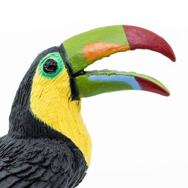 Toucan with open red, green, and orange beak. Yellow face with green eyes and black feathers. Blue Feet.
