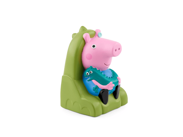 A Peppa Pig toy figure sitting in a green dinosaur-shaped chair, holding a blue dinosaur toy, on a plain white background.