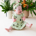 Baby wearing An all-over print featuring unripe avocados on the branch, whole and halved ripe avocados with their stems and leaves, and halved avocados with their pits, over a soft yellow green background color called Pistachio.