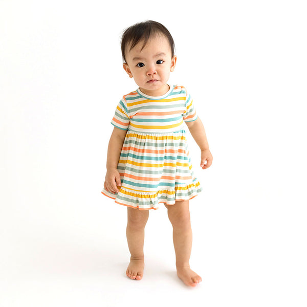 Toddler wearing This Bodysuit dress has a white background with horizontal stripes. Aqua, Mustard, Sage Green, and Coral