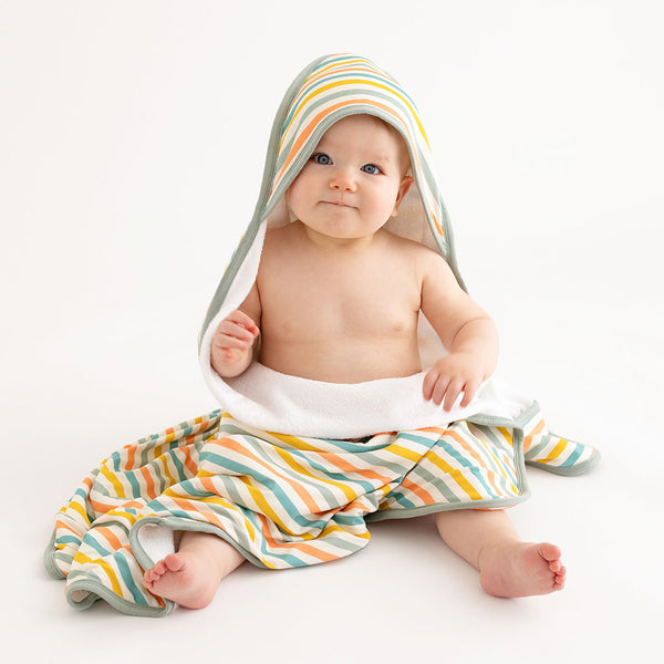 Baby wearing hooded towel which has a white background with horizontal stripes. Aqua, Mustard, Sage Green, and Coral