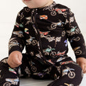 Boy wearing zippered footie in supermini print. Print is black with mini dirt bikes and flags.