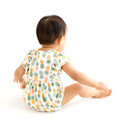 Child sitting with back to camera wearing the Flutter Sleeve Romper with easy diaper change snaps. This is the This print has a white background with Pineapple print. Light Green, Dark green, Orange, and Yellow Pineapples are repeated all over with a white background