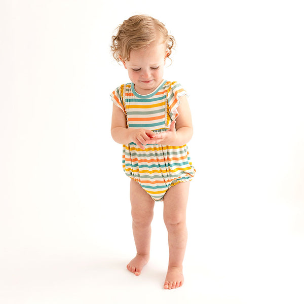 Toddler wearing the romper which has a white background with horizontal stripes. Aqua, Mustard, Sage Green, and Coral