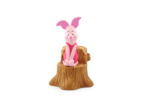Pink piglet figurine sitting on a wooden stump against a white background