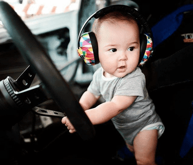 Baby wearing baby ear muffs. The print is colorful prisms