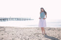 Woman standing on a beach with a blurred pier in the background