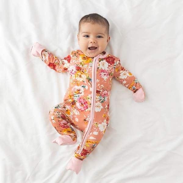 One piece pj. Print is orange, red, yellow and white floral on a peachy background.