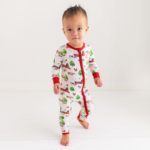 Toddler in one piece. Country farm print on a cream background. Zipper, wrists and foot cuffs are red.