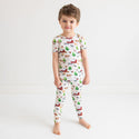 Boy standing in short sleeve long pants pajama set. Country farm print on a cream background.