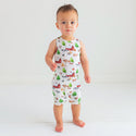 Toddler boy standing in a romper. Country farm print on a cream background.