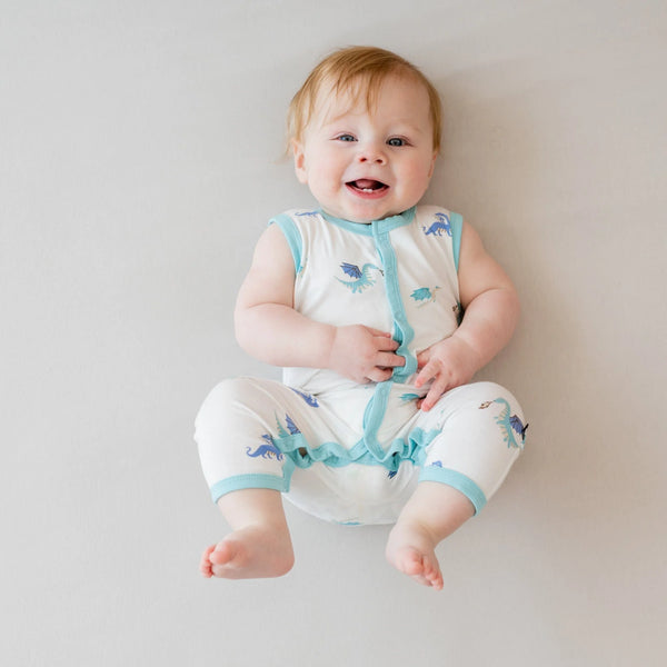 Infant wearing white romper with aqua dragons. Sleeve, neck and snap trim is aqua.