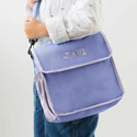 Child carrying Lavender lunch tote with shoulder strap. The tote has lilac trim around the edges.