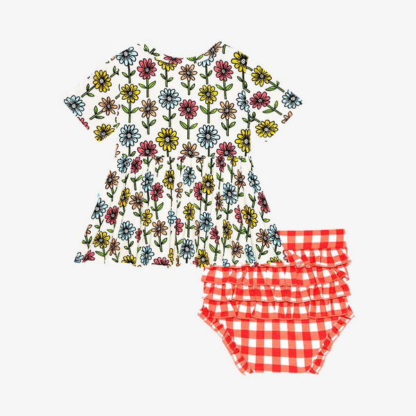 Two-Piece outfit.  Includes a Peplum Top. The Print is a floral on a cream background. The Flowers are single daisies on stems and vary in color. Light Blue, Yellow, light orange, and pink. The Bloomer bottoms are a red and white gingham print and have adorable ruffles on the back.